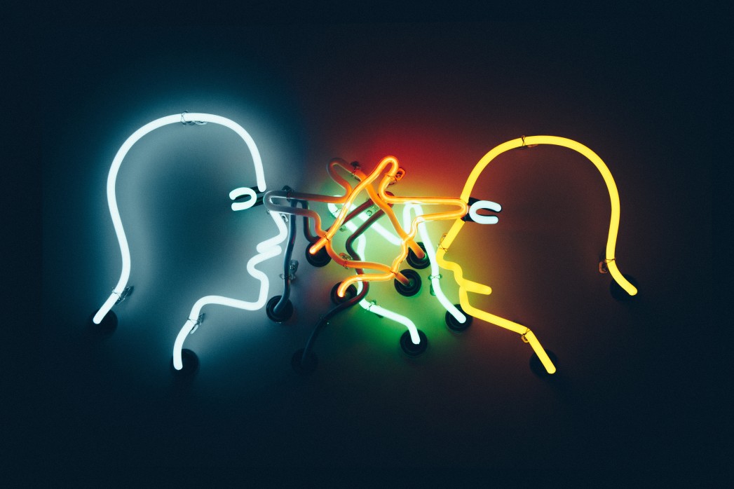 The outline of two human heads in an argument, constructed out of neon.