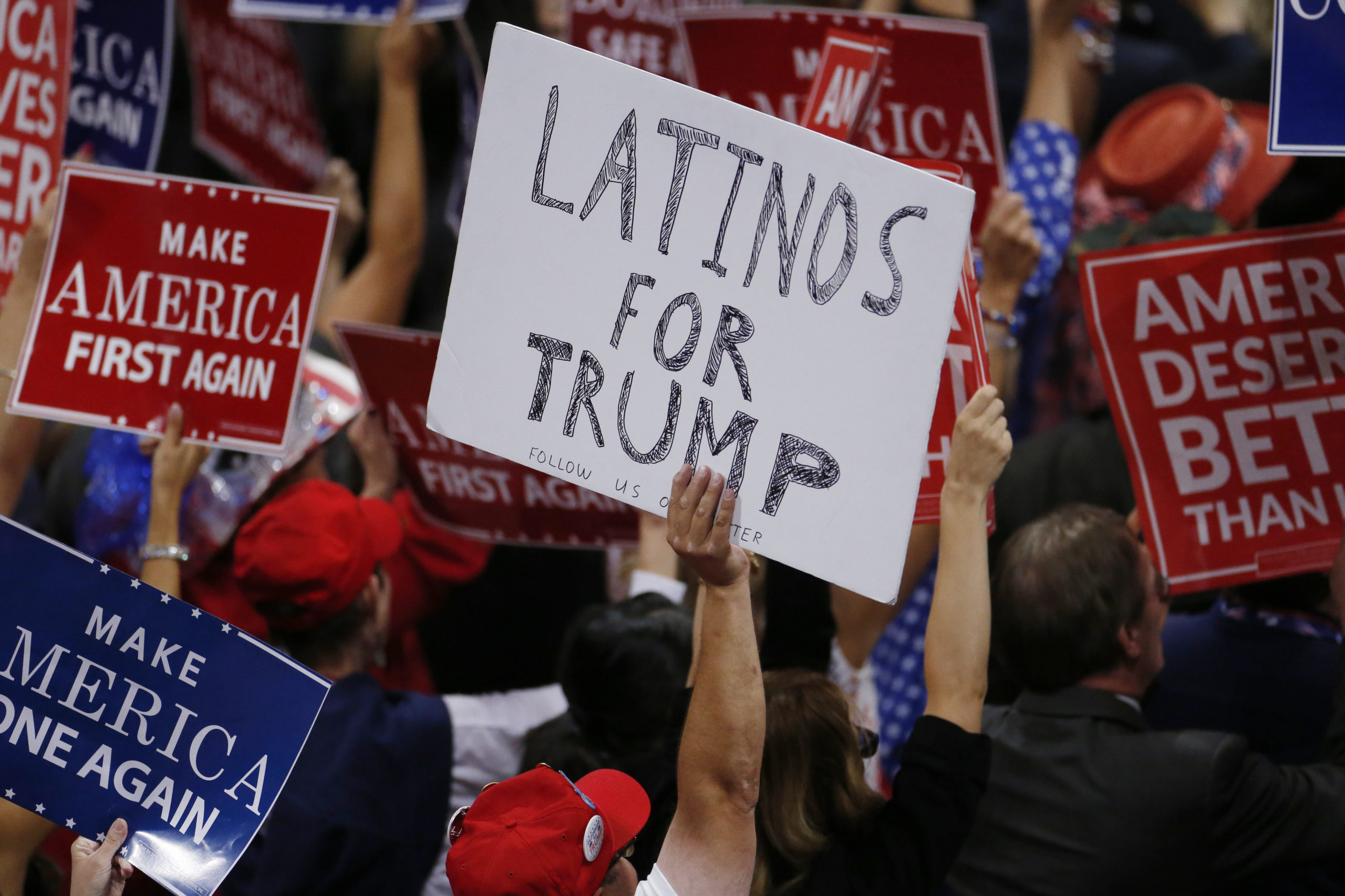 Man holding a sign that says "Latinos for Trump"