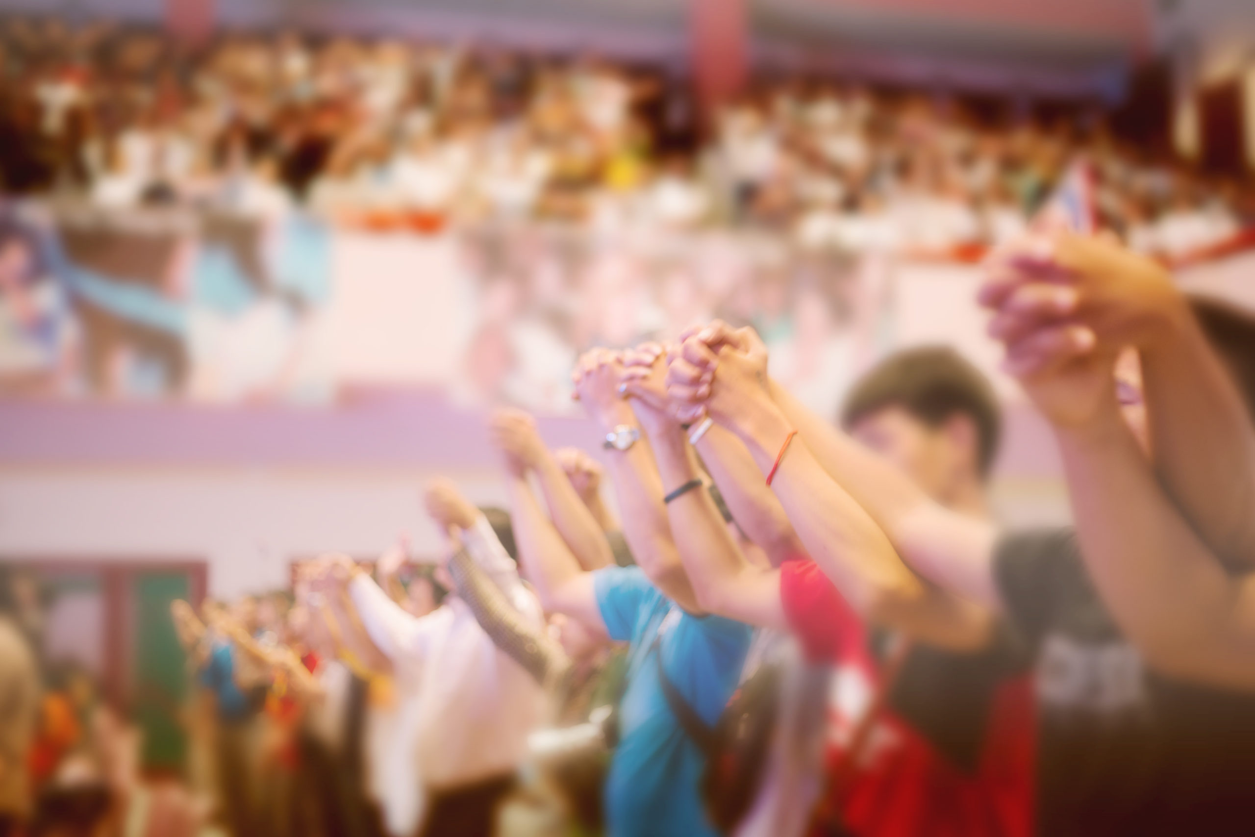 Photograph of people holding hands in prayer and worship