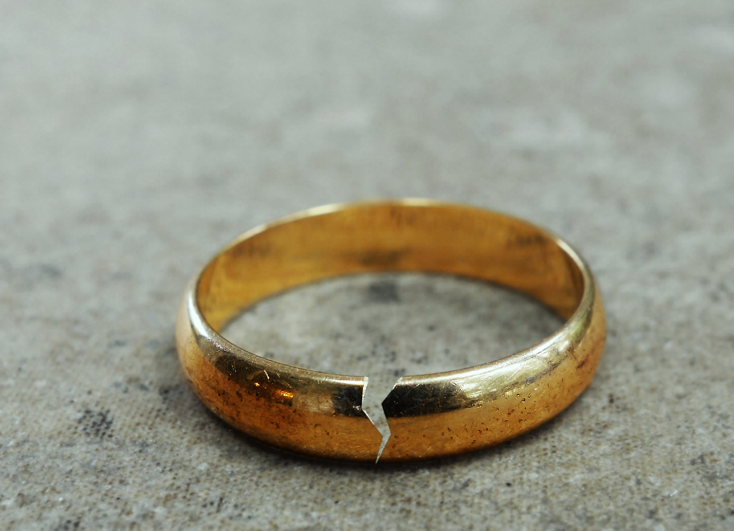 An image of a broken wedding ring. There is a significant crack in the ring which is showed in the image foreground.