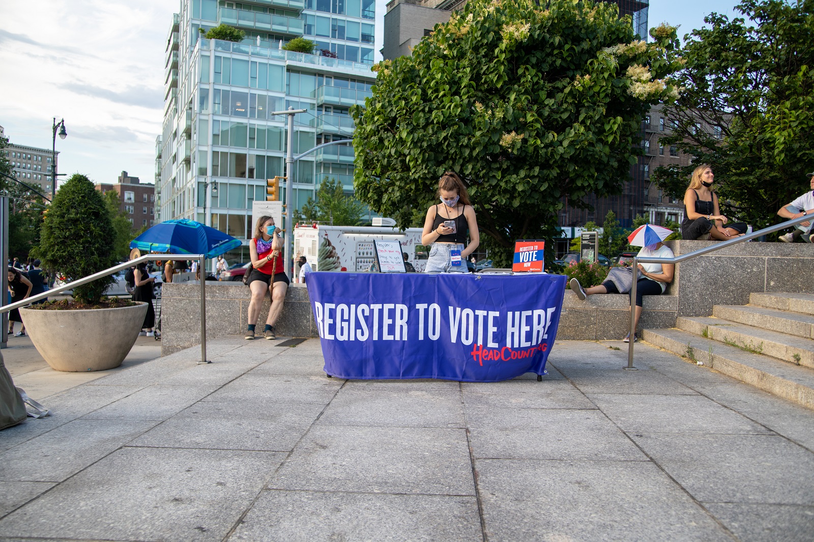 An image of a woman standing over a table to register people to vote.