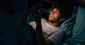 Young man laying down scrolling on his cell phone